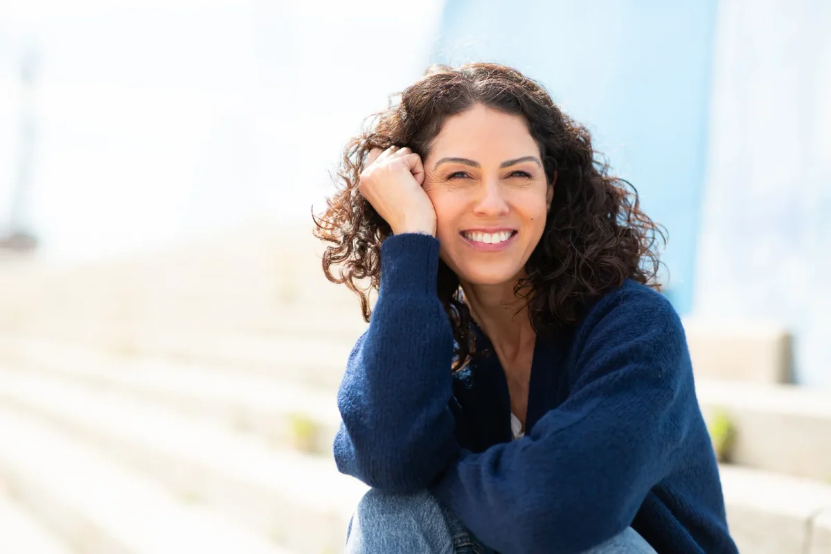 Smiling woman with curly hair wearing a blue sweater
