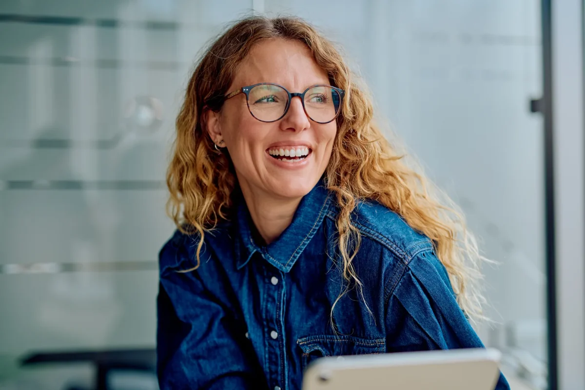Smiling woman with glasses wearing a denim shirt
